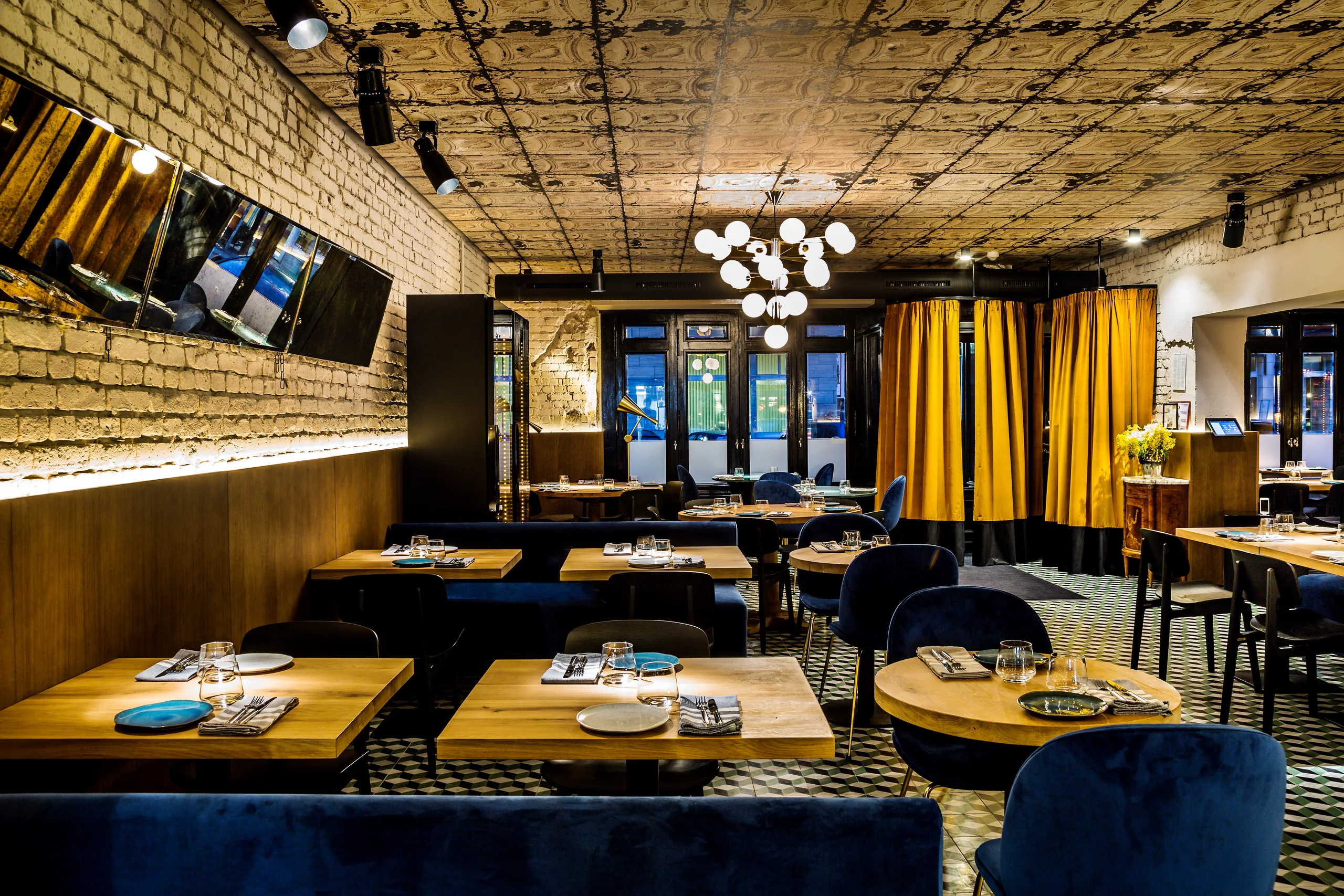 Dining area near the front windows with mustard curtains and booth seating